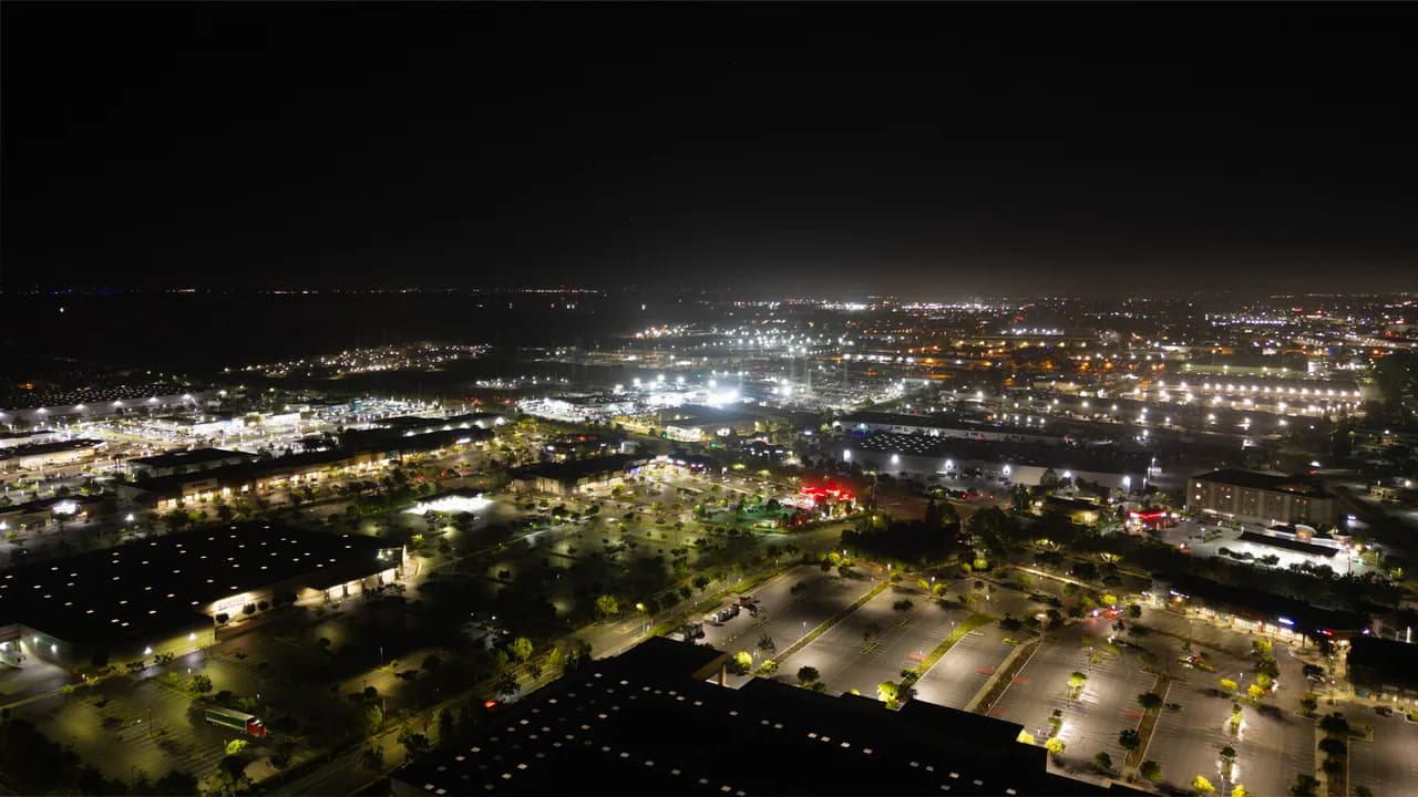 Rows of parking spaces and low rooftops lead toward a broad grid of city lights. After Dark photo 5 of 9.