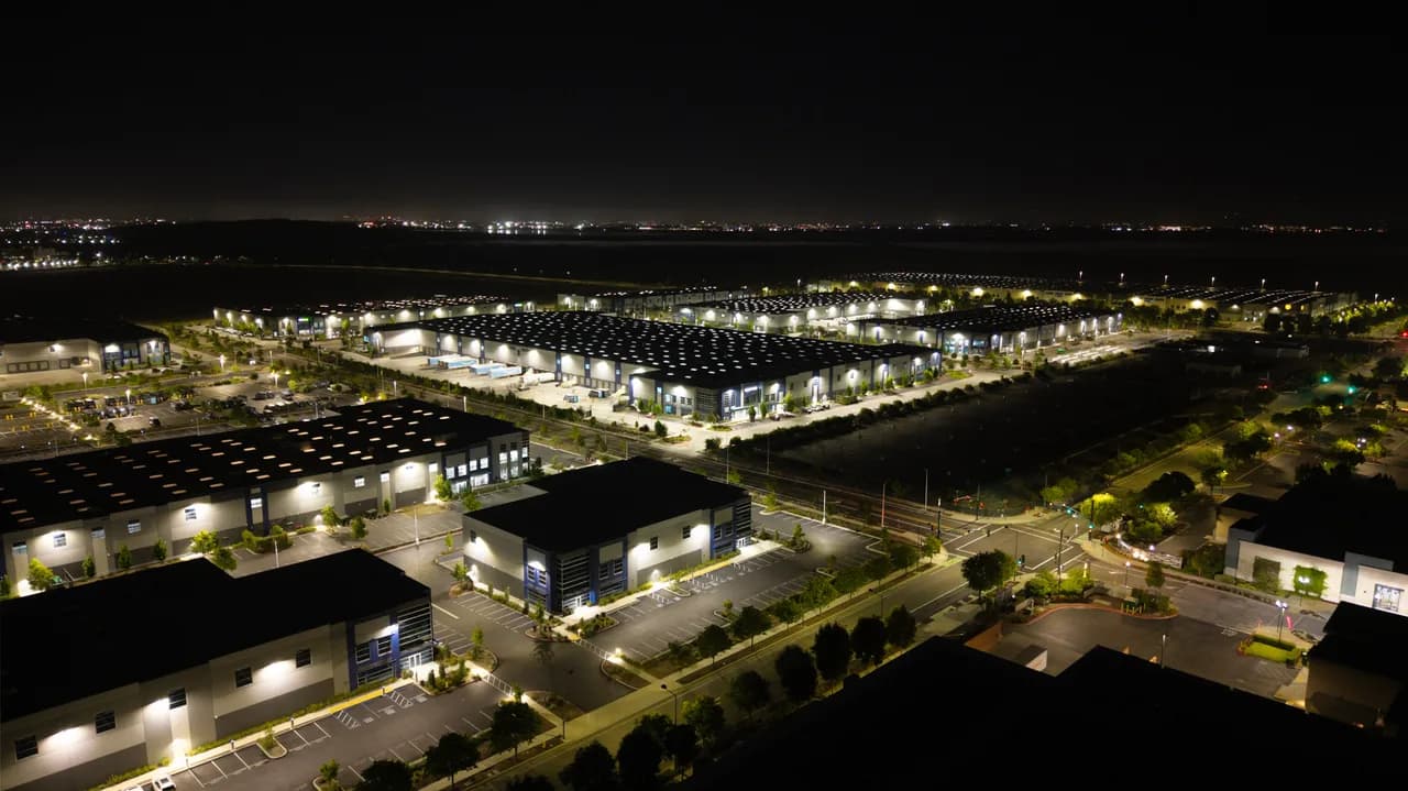 Long rows of rooftop panels and brightly lit building edges form a geometric pattern at night. After Dark photo 7 of 9.