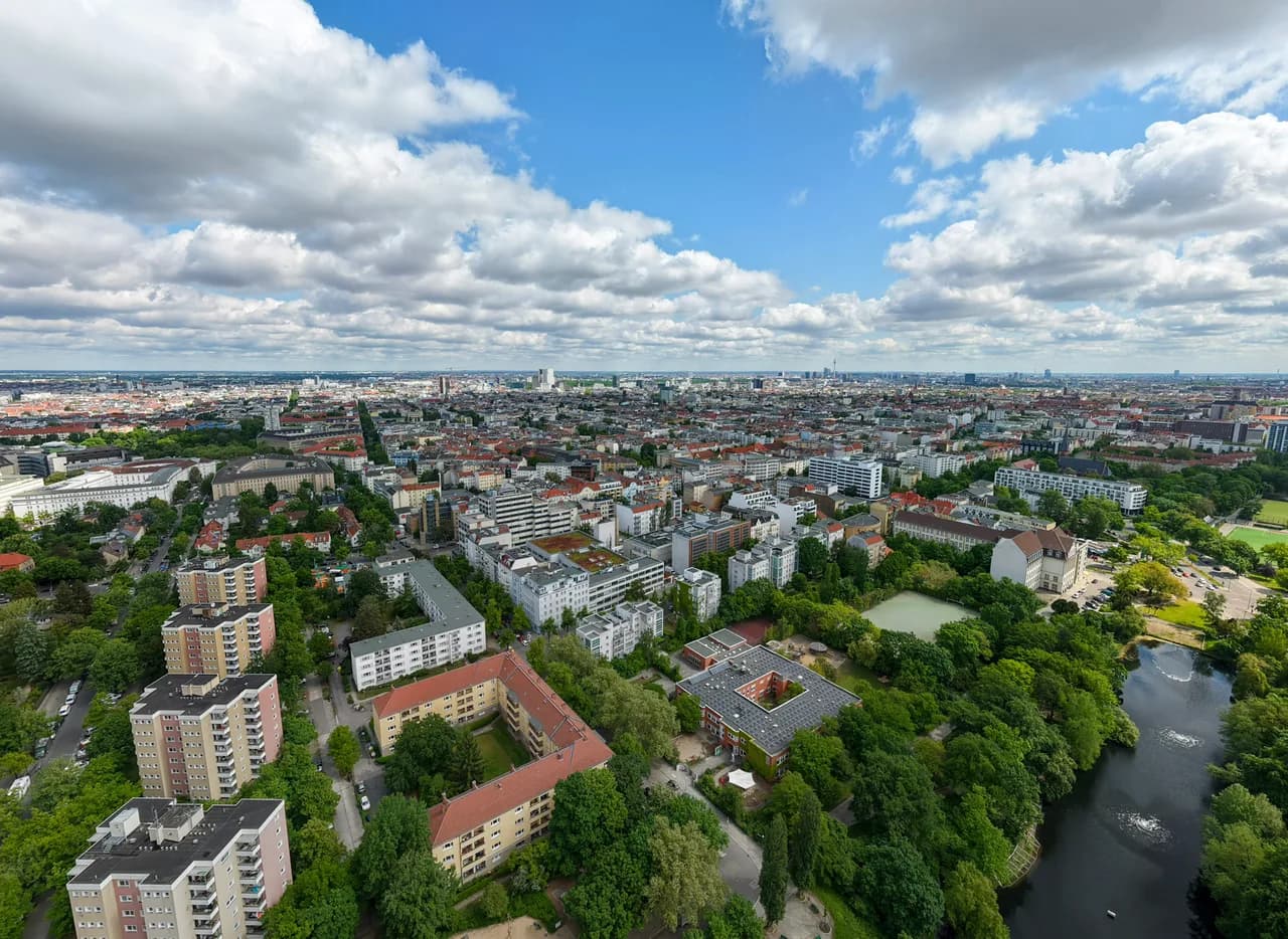 A river curves past leafy neighborhoods and red-roofed buildings beneath scattered clouds. Coast & City photo 2 of 11.