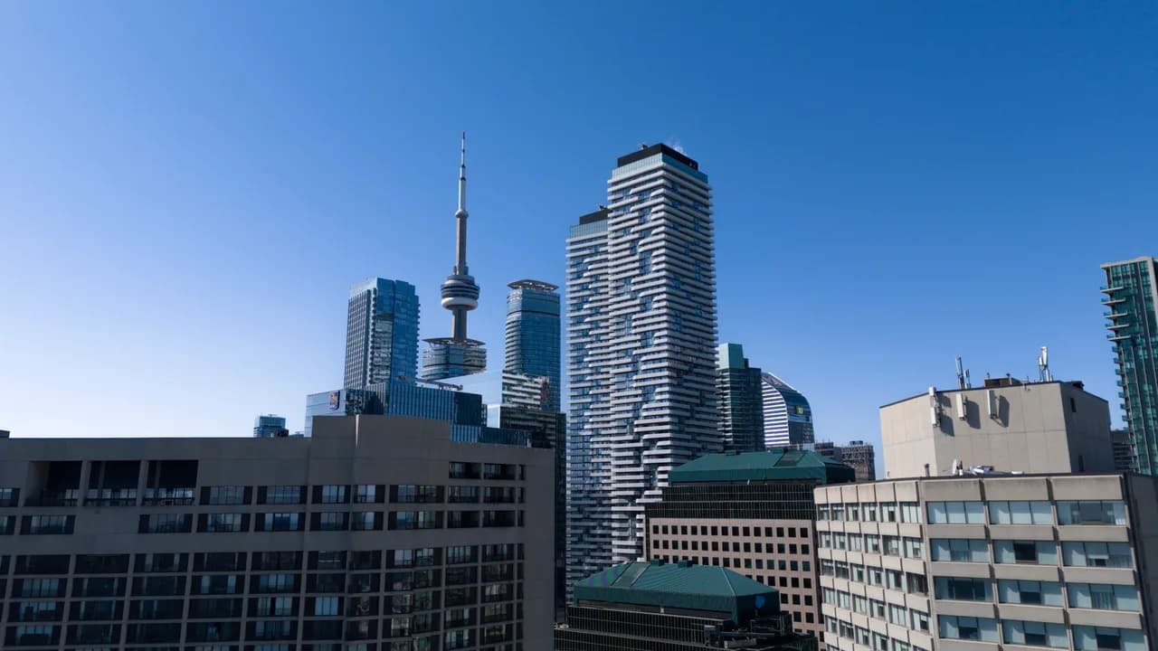 A slender observation tower rises among high-rise buildings against a clear blue sky. Coast & City photo 3 of 11.